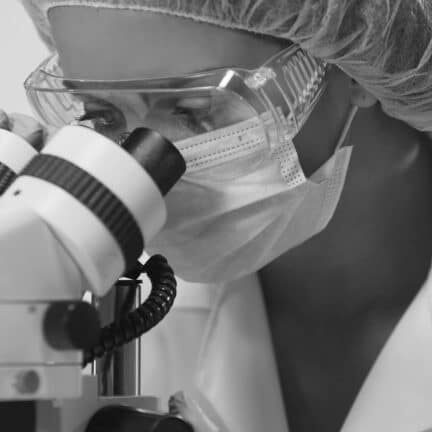 Lab worker examines specimen under microscope