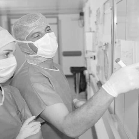 Doctor and nurse in PPE planning patient schedules on whiteboard in procedure area